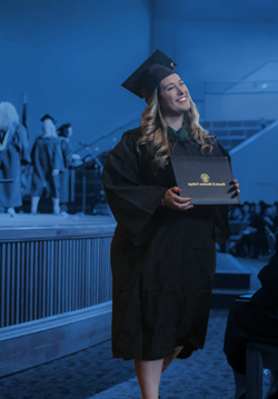毕业典礼上，米娅·柯林斯拿着毕业证书走上舞台